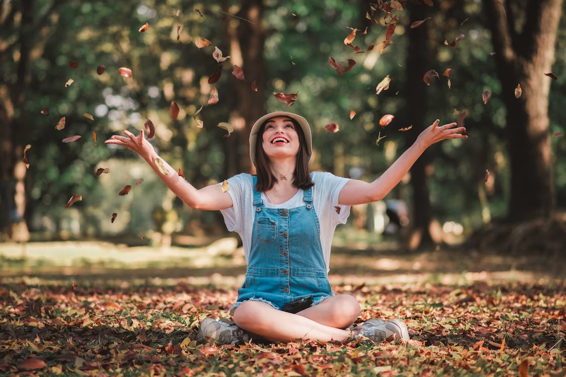 woman sitting in a park with leaves falling