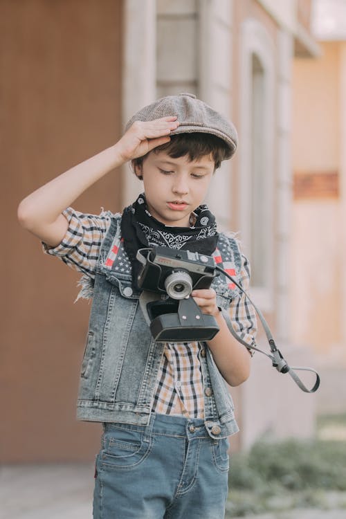Boy in Blue Denim Jacket Holding Black and Gray Camera