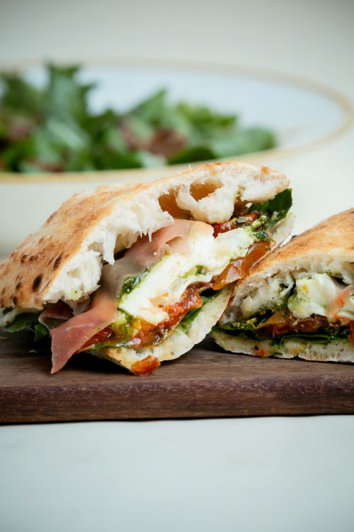 Free Sliced gourmet sandwich with fresh greens and melted cheese on wooden board. Stock Photo