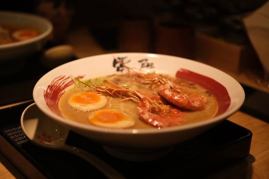 A bowl of savory shrimp ramen garnished with soft-boiled eggs, offering rich flavors.