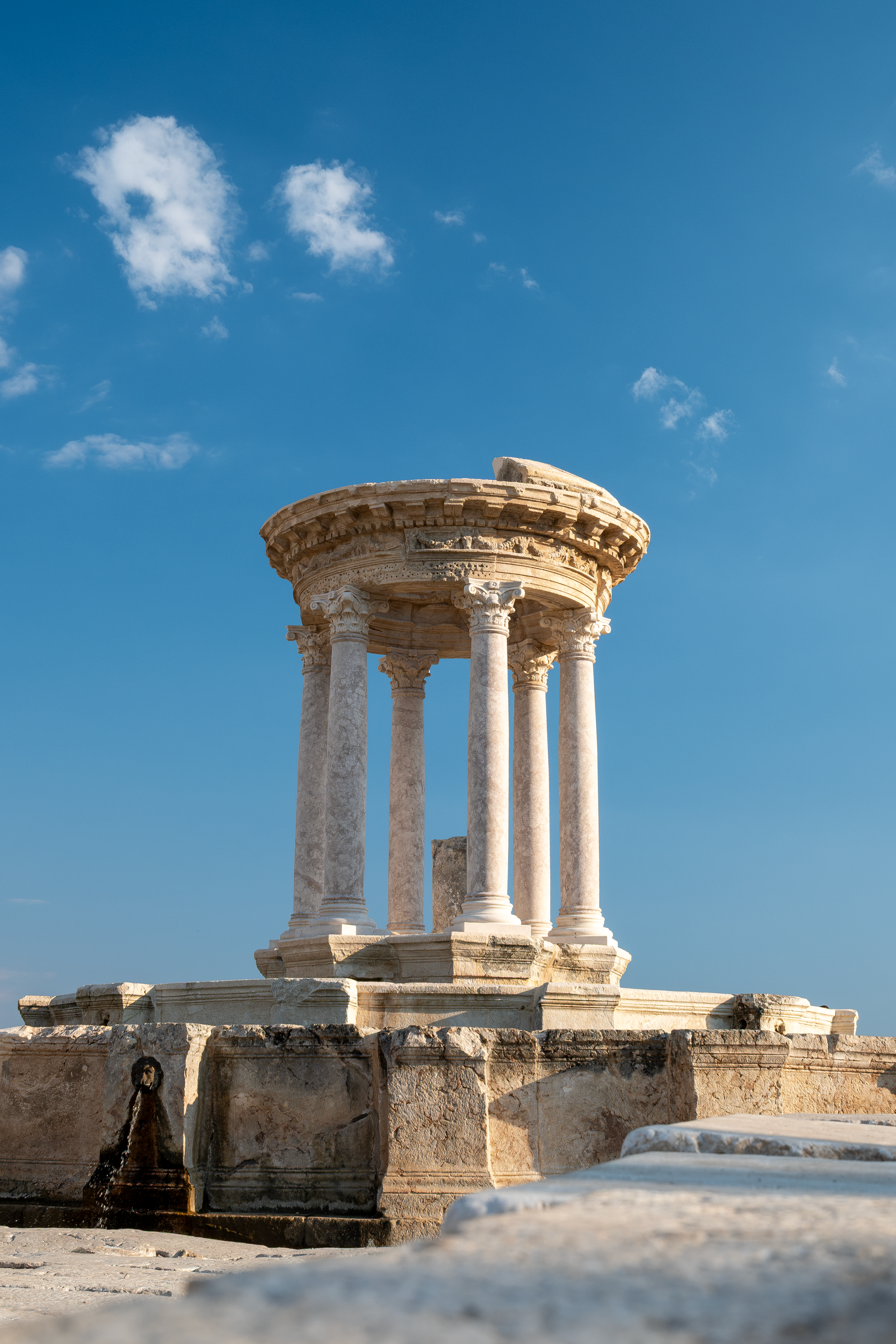 A beautiful nymphaeum with Corinthian columns under a clear blue sky in Burdur, Türkiye.