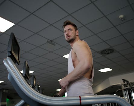 Athletic man working out on a treadmill in a modern gym, showcasing strength and determination.
