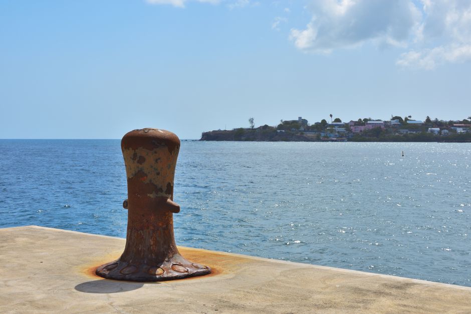 A rusted mooring bollard at a concrete dock in St Kitts overlooking the Caribbean Sea.