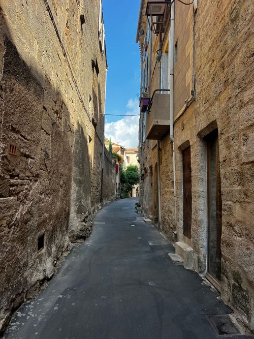 Free Explore the picturesque narrow stone alleyway in a historic Mediterranean village under a blue sky. Stock Photo