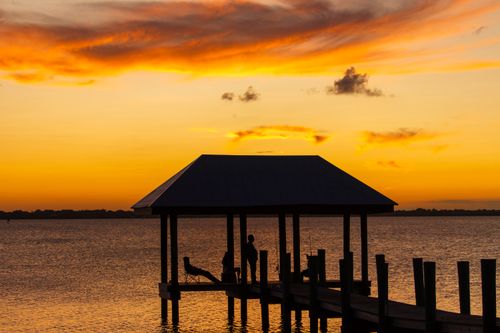 Free Two people enjoy a tranquil sunset under a dock pavilion in Florida. Stock Photo