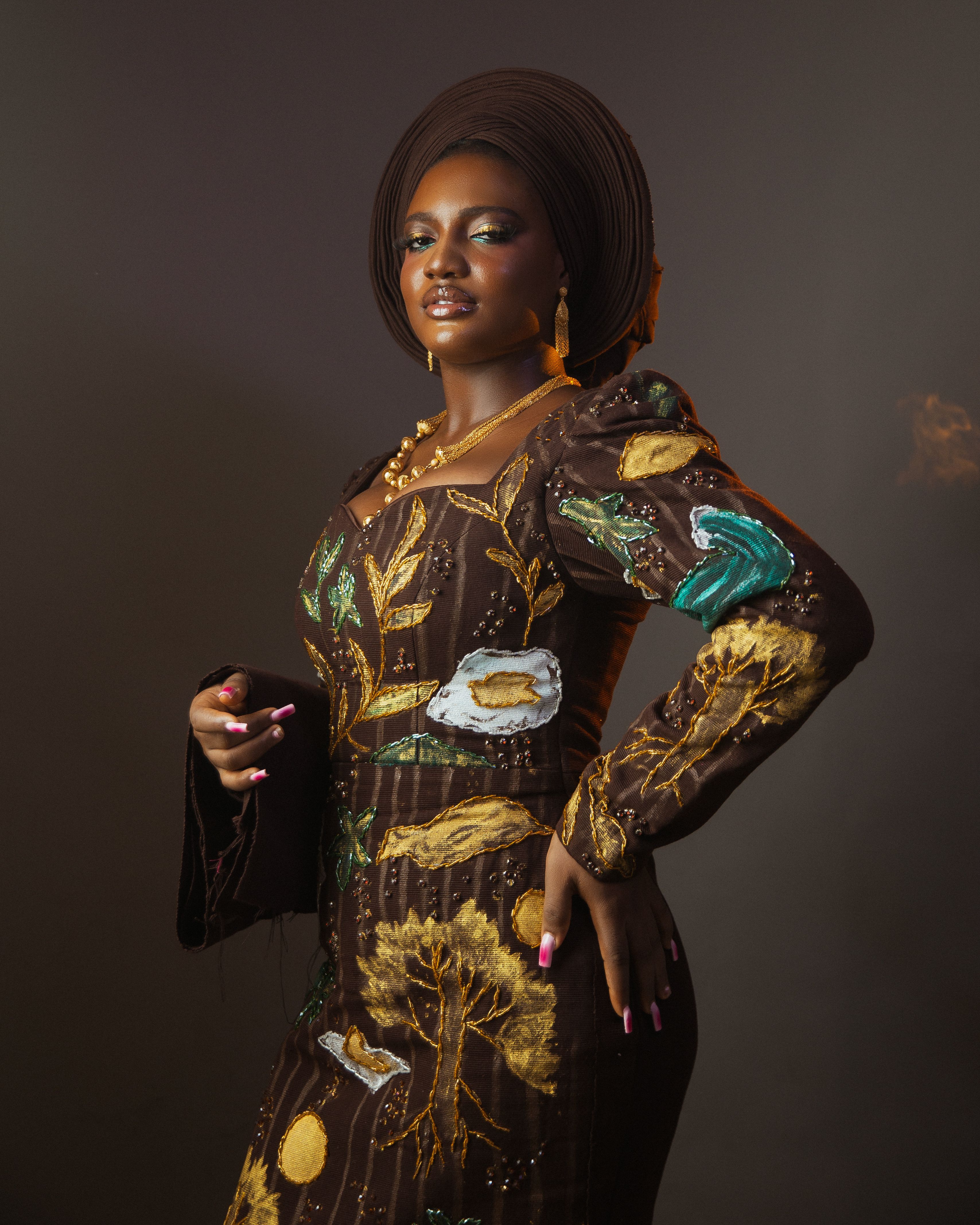Stylish portrait of a woman in colorful Nigerian traditional dress with intricate patterns, standing confidently.