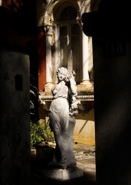 Free Elegant classical statue illuminated by sunlight in a serene courtyard setting. Stock Photo