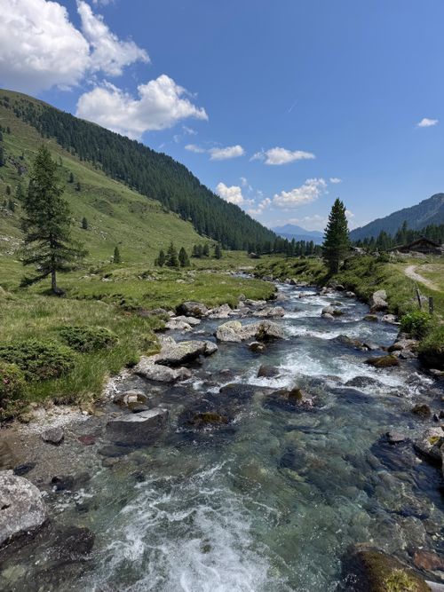 Free Beautiful alpine stream flowing through lush Tyrolean landscape with blue skies and mountains. Stock Photo
