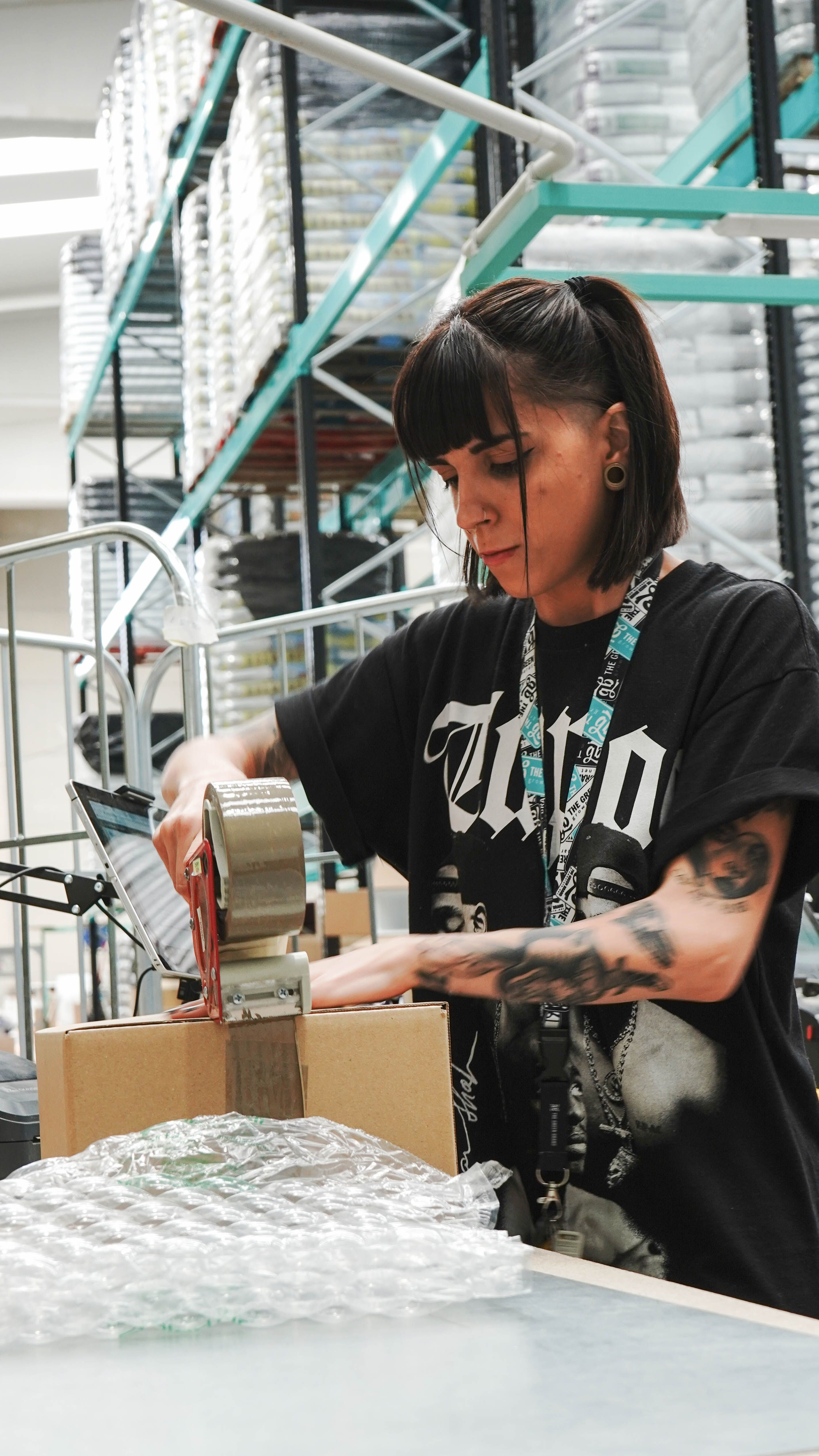 Woman worker in a Spanish warehouse sealing a package for logistics.