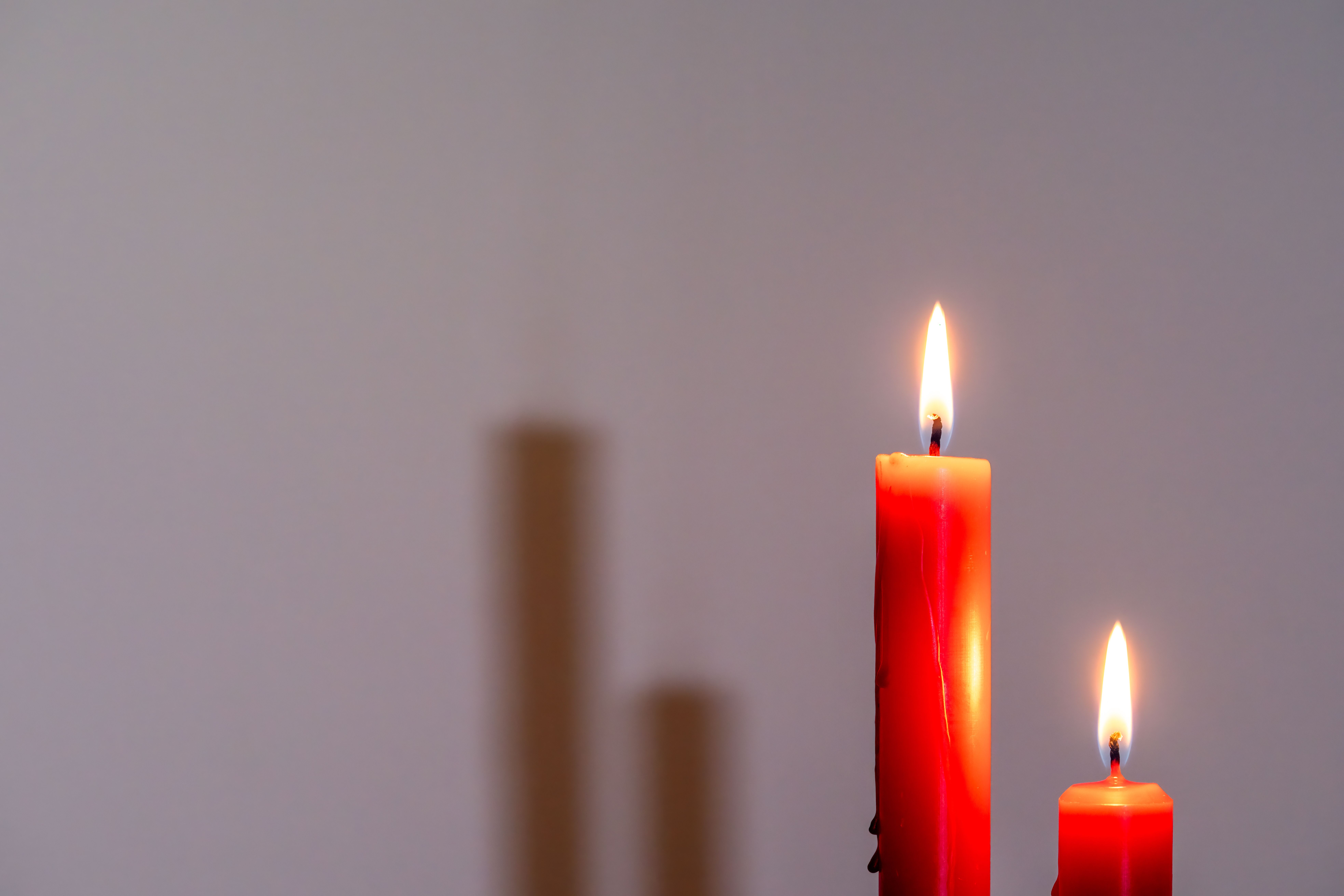 Fotomural Dos velas rojas que arden suavemente sobre un fondo neutro, creando un ambiente cálido.