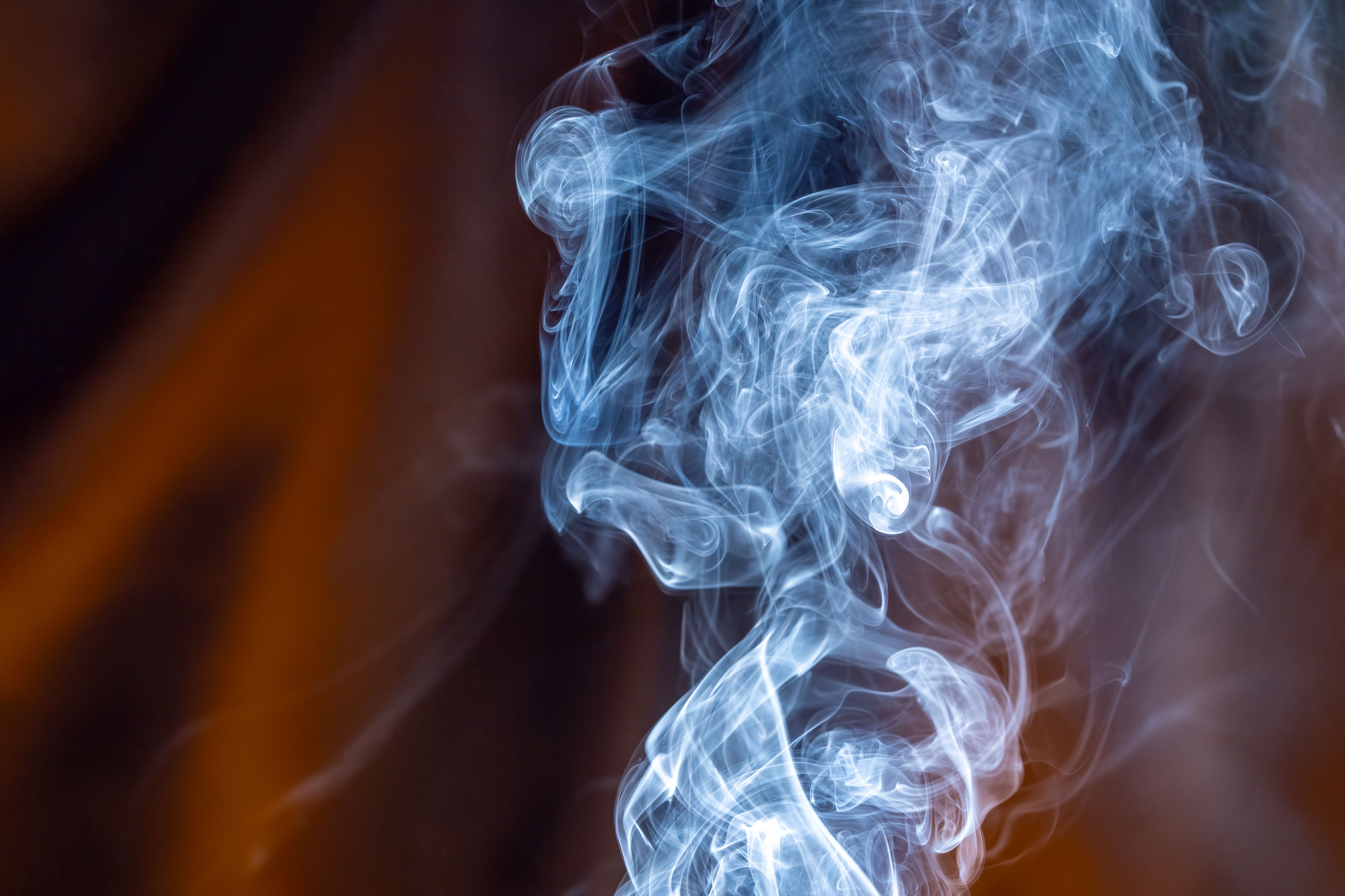 Fotomural Hermosas pinceladas de humo azul se arremolinan elegantemente sobre un fondo marrón cálido, creando una imagen abstracta fascinante.