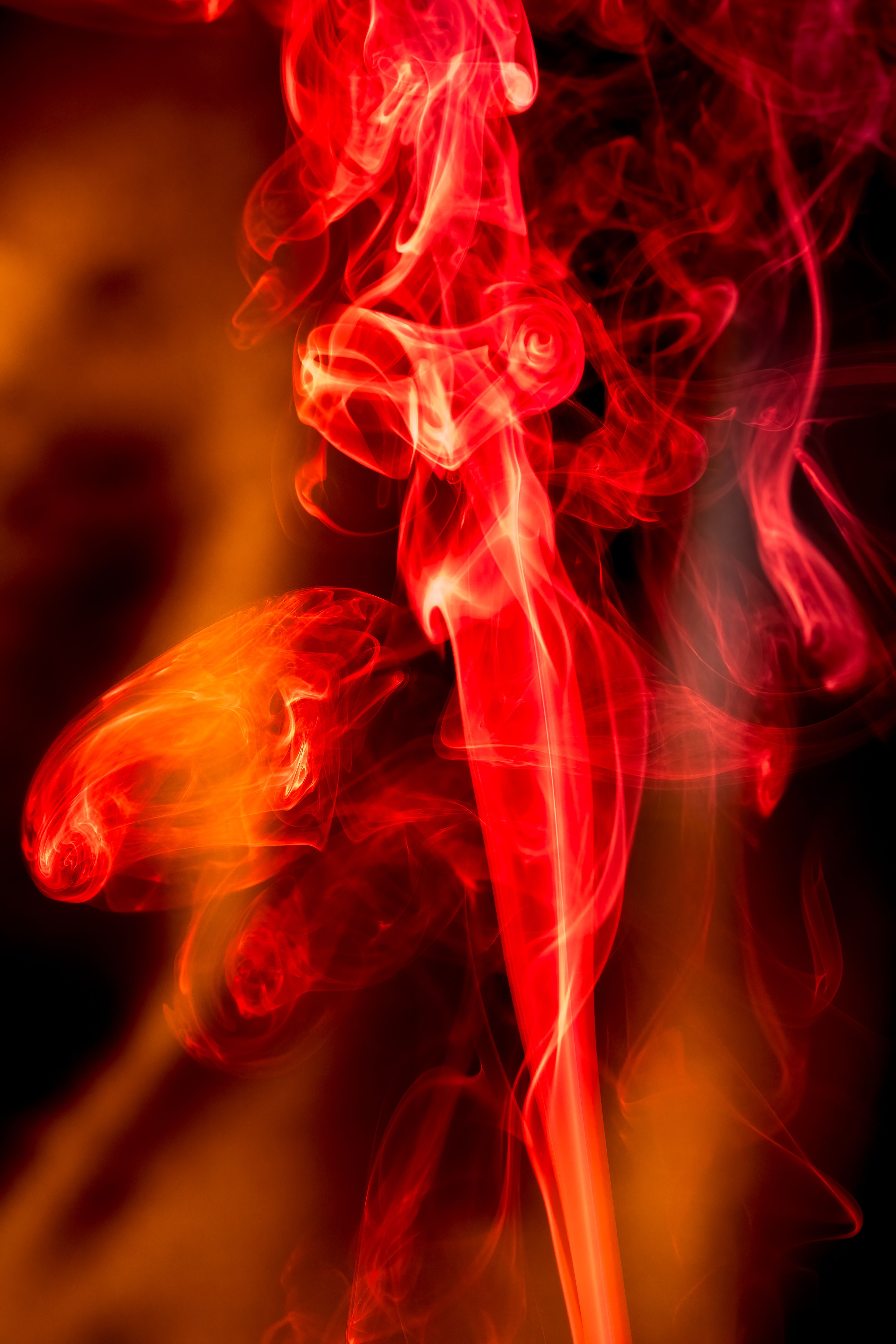 Fotomural Imagen abstracta y vibrante que muestra humo rojo y naranja arremolinándose sobre un fondo negro.