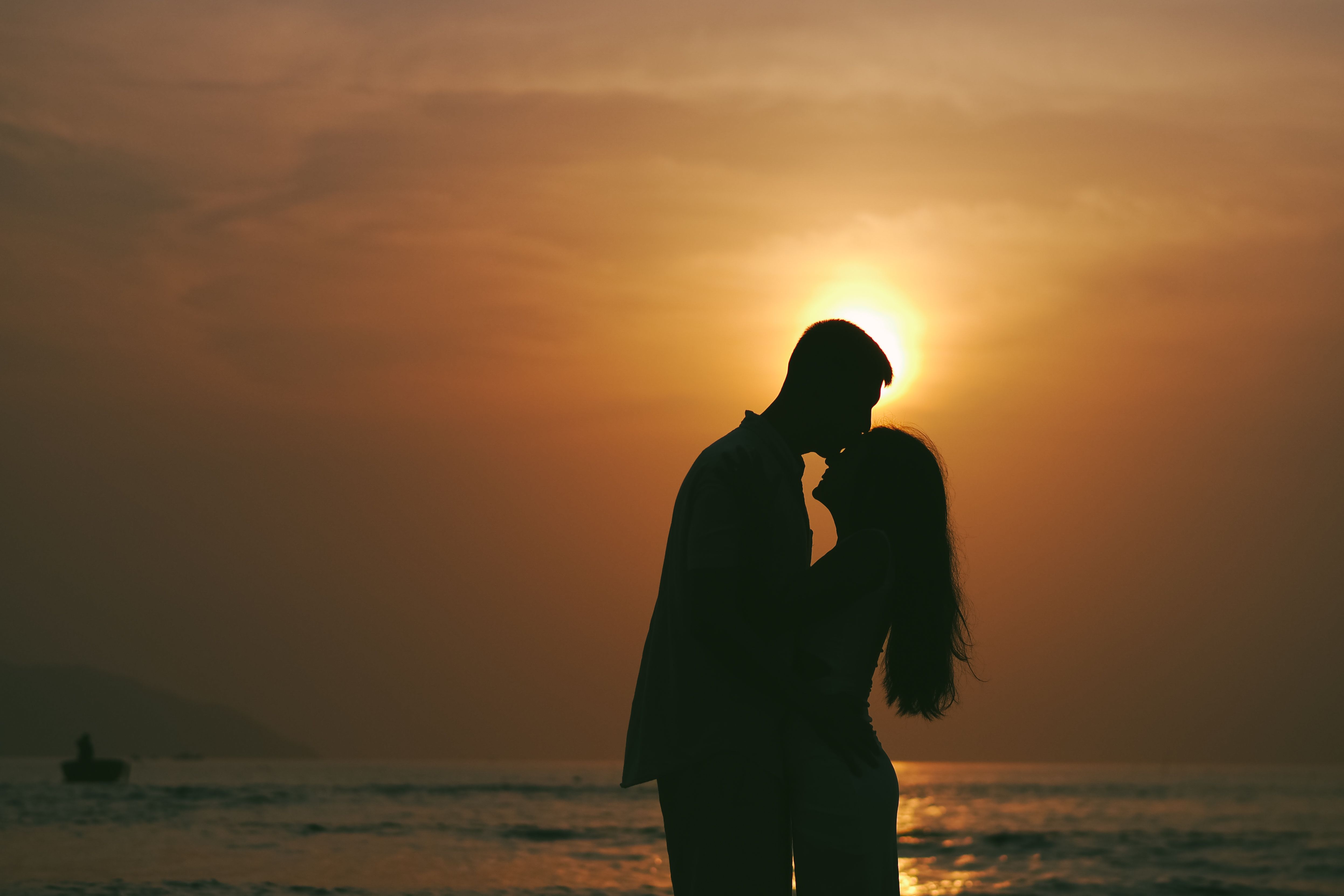 A couple shares a loving moment as the sun sets behind them on Da Nang beach, Vietnam.