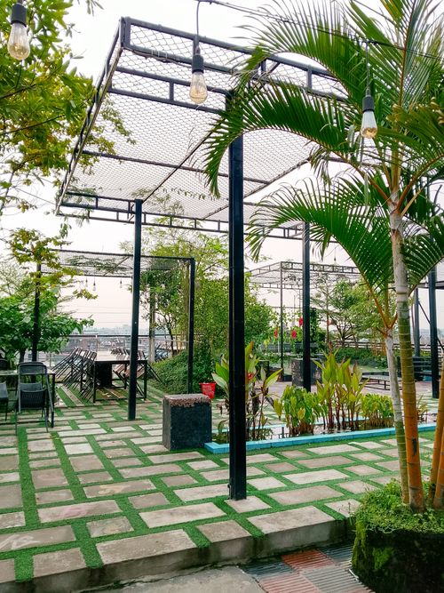 Free Spacious outdoor patio with lush greenery, pergolas, and vintage lighting, perfect for relaxation. Stock Photo