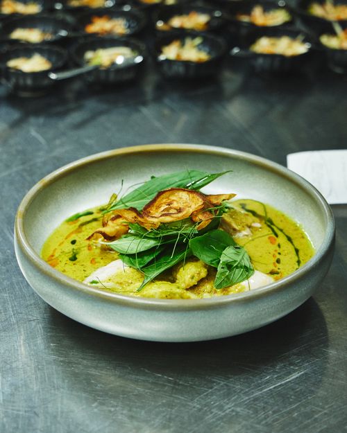 Free Flavorful green curry dish garnished with herbs, captured in a sleek ceramic bowl. Stock Photo
