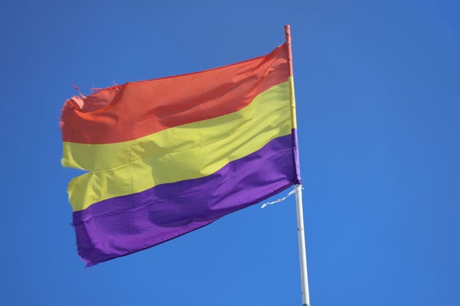 Una vibrante bandera republicana española ondeando contra un cielo azul despejado en El Puerto de Santa María, España.