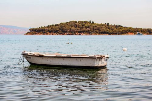 Free A lone boat floats peacefully in clear waters with a wooded island in the distance. Stock Photo