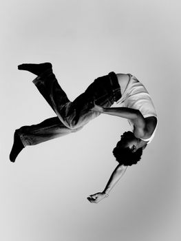 Artistic black and white photo of a person performing an acrobatic flip, showcasing movement and grace.