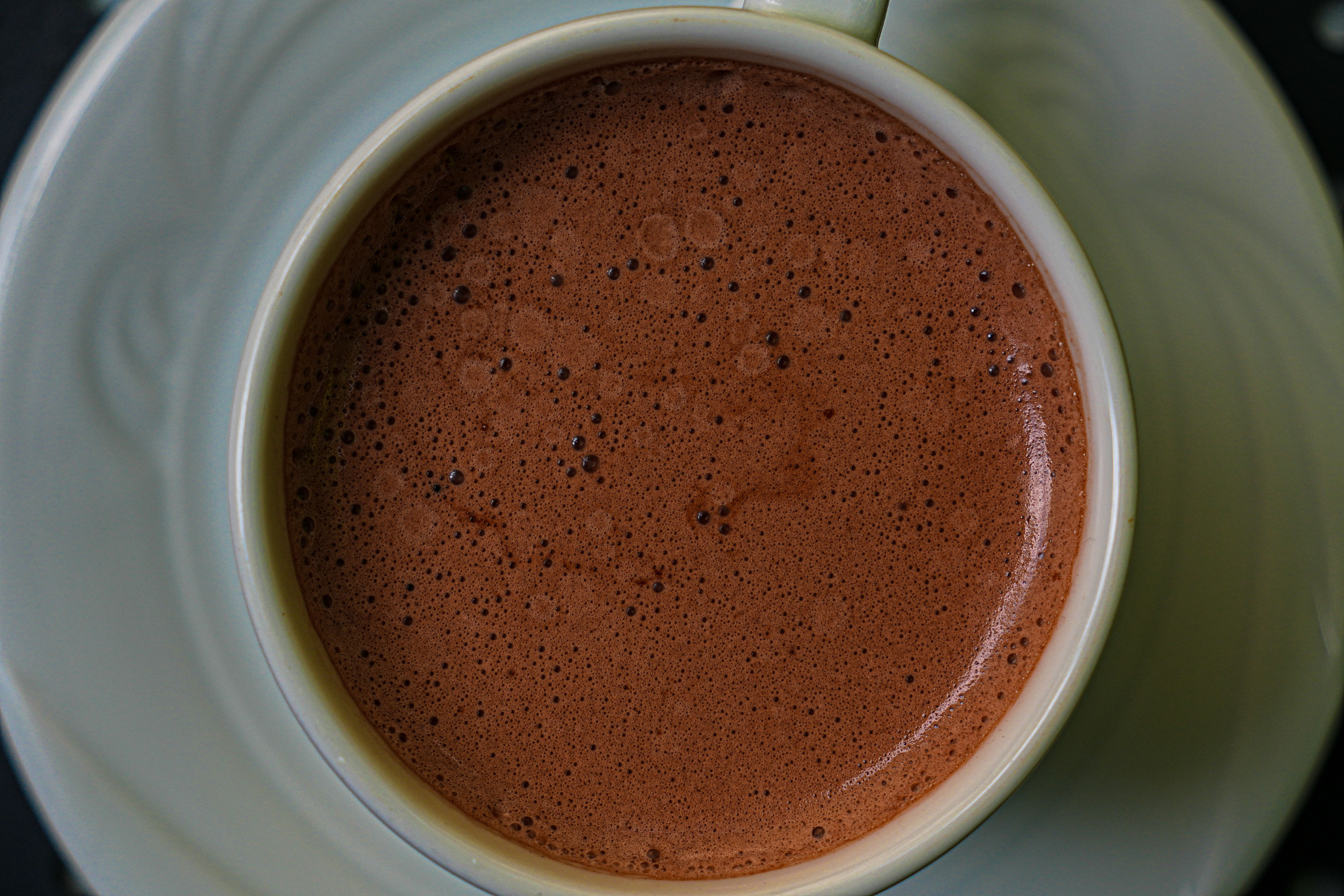 Close-up of frothy hot chocolate in a ceramic cup, providing a cozy and inviting feel.