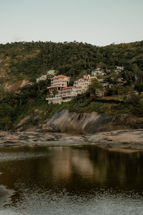 Free Picturesque hillside homes surrounded by lush greenery, reflecting in a tranquil lagoon. Stock Photo