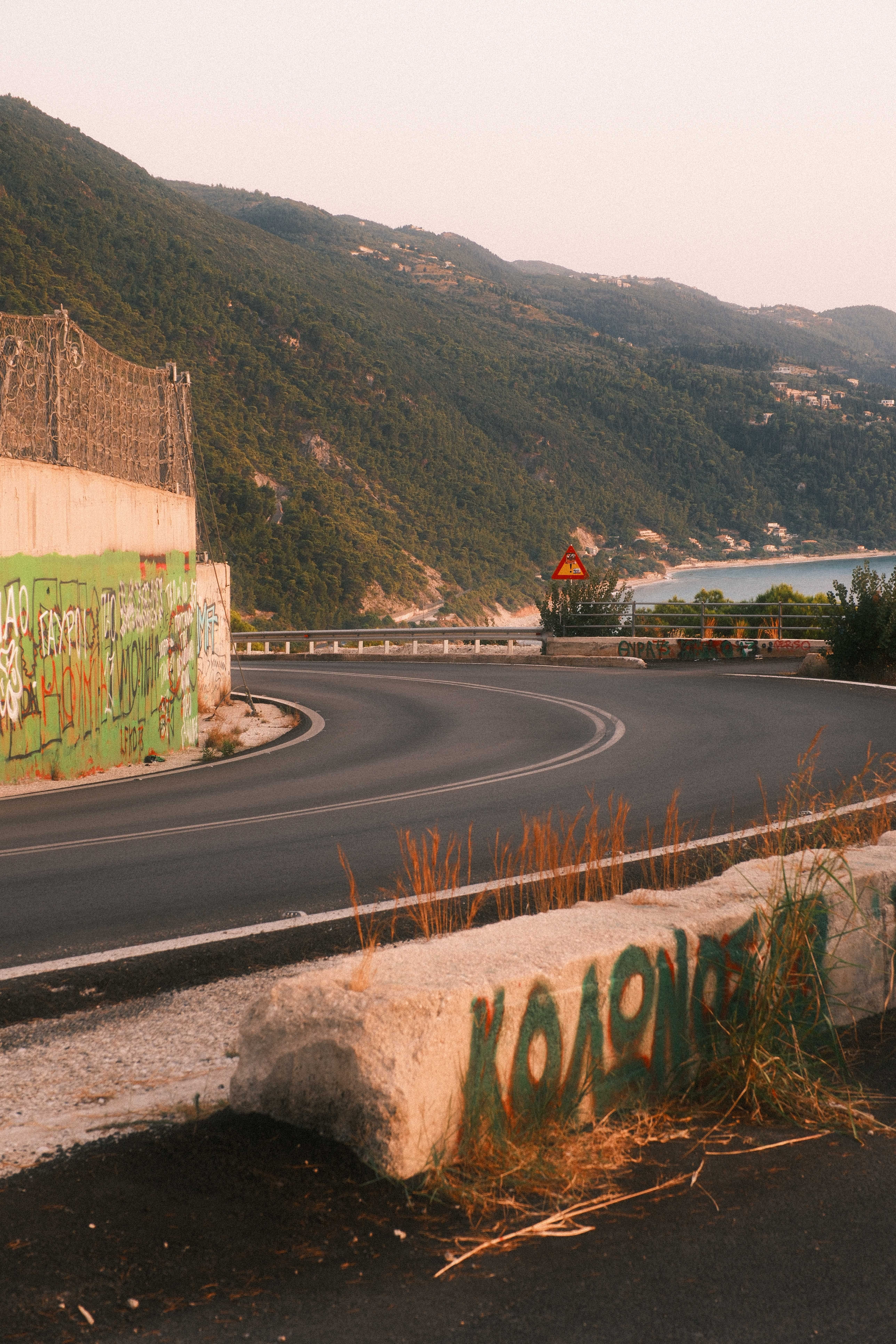 Winding road in Greece with sea view at sunset, perfect for travel themes.