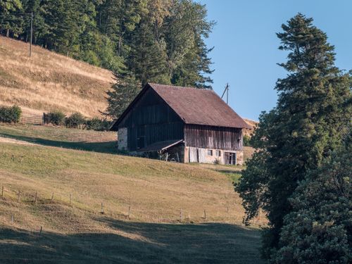 Free A charming old barn surrounded by scenic countryside on a sunny day. Stock Photo