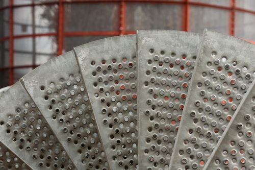 Free Close-up view of a perforated metal grate in an industrial setting with red framework. Stock Photo