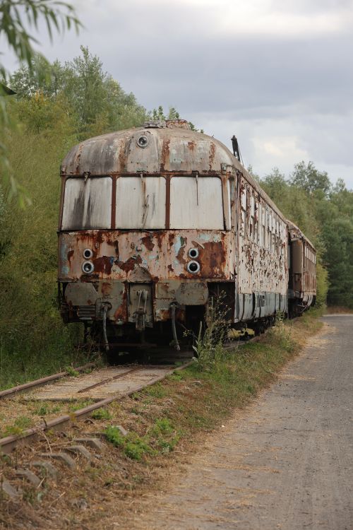 Free Photograph of a vintage, rusted train carriage abandoned on an overgrown railway track. Stock Photo
