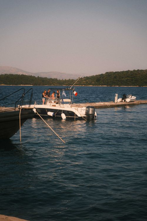 Free A tranquil scene of boats docked at a coastline under soft summer sunlight. Stock Photo