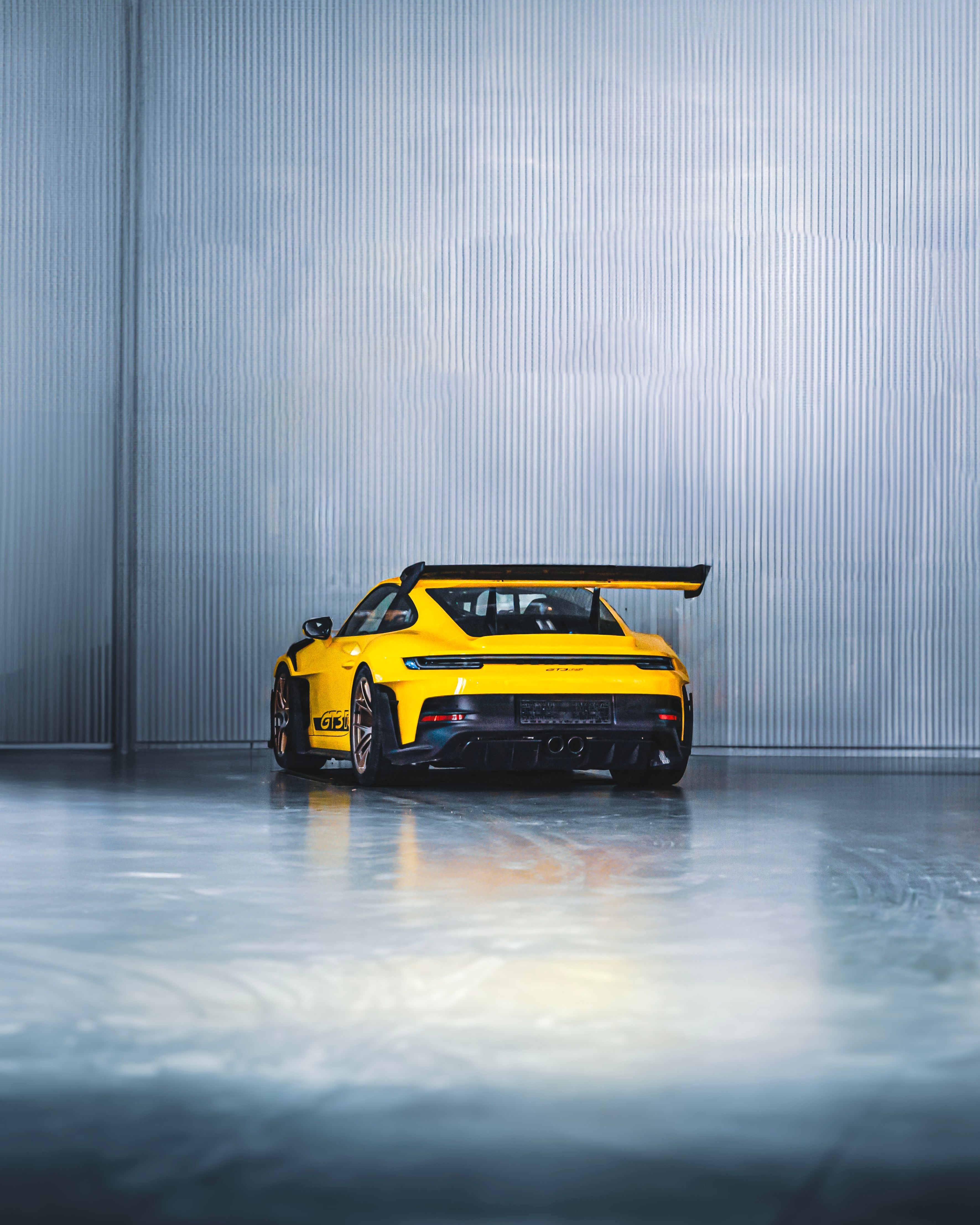 A striking yellow sports car parked in a sleek modern garage with industrial design elements and ambient lighting.