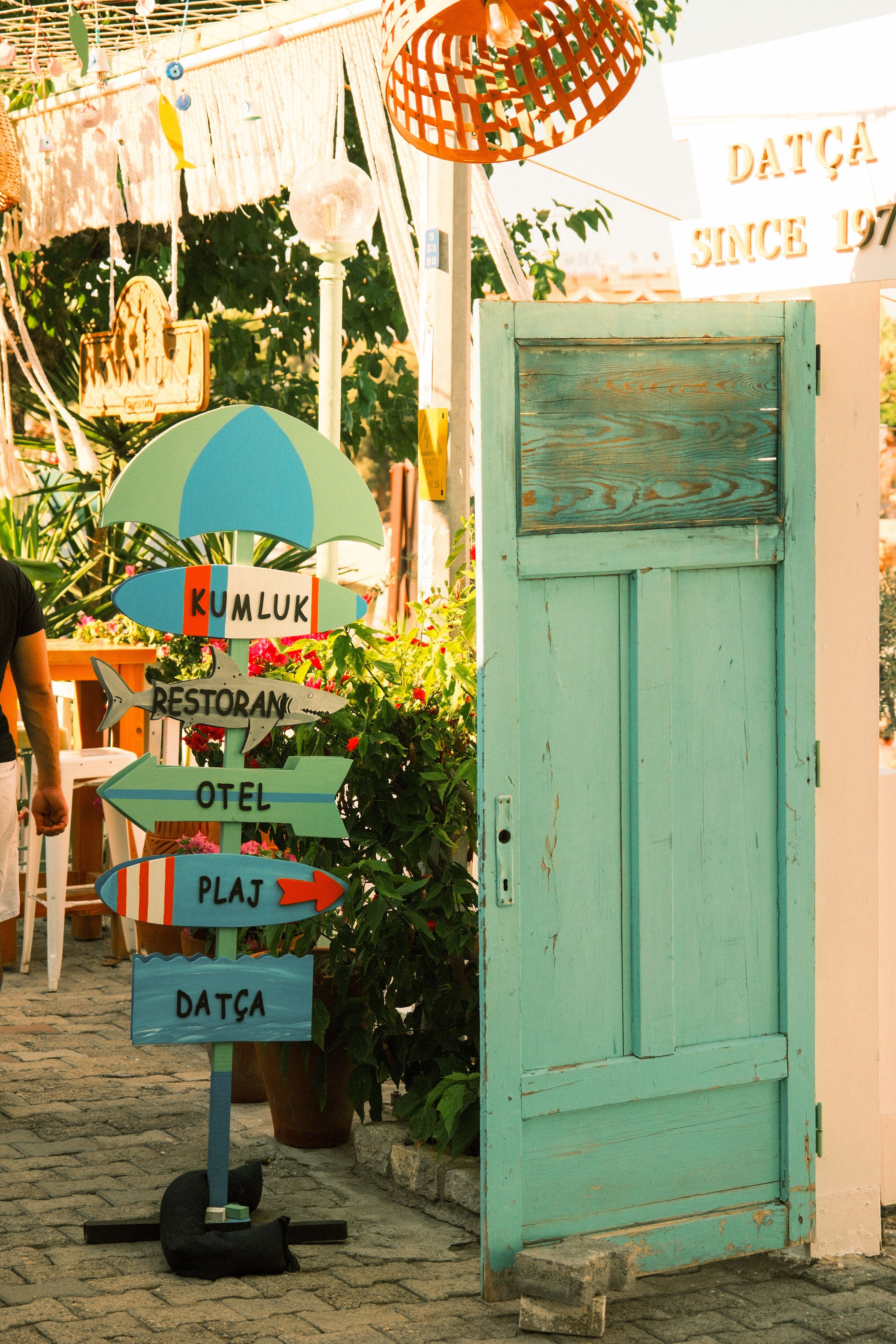 Vibrant beach sign and rustic door in sunny Datça, Turkey.