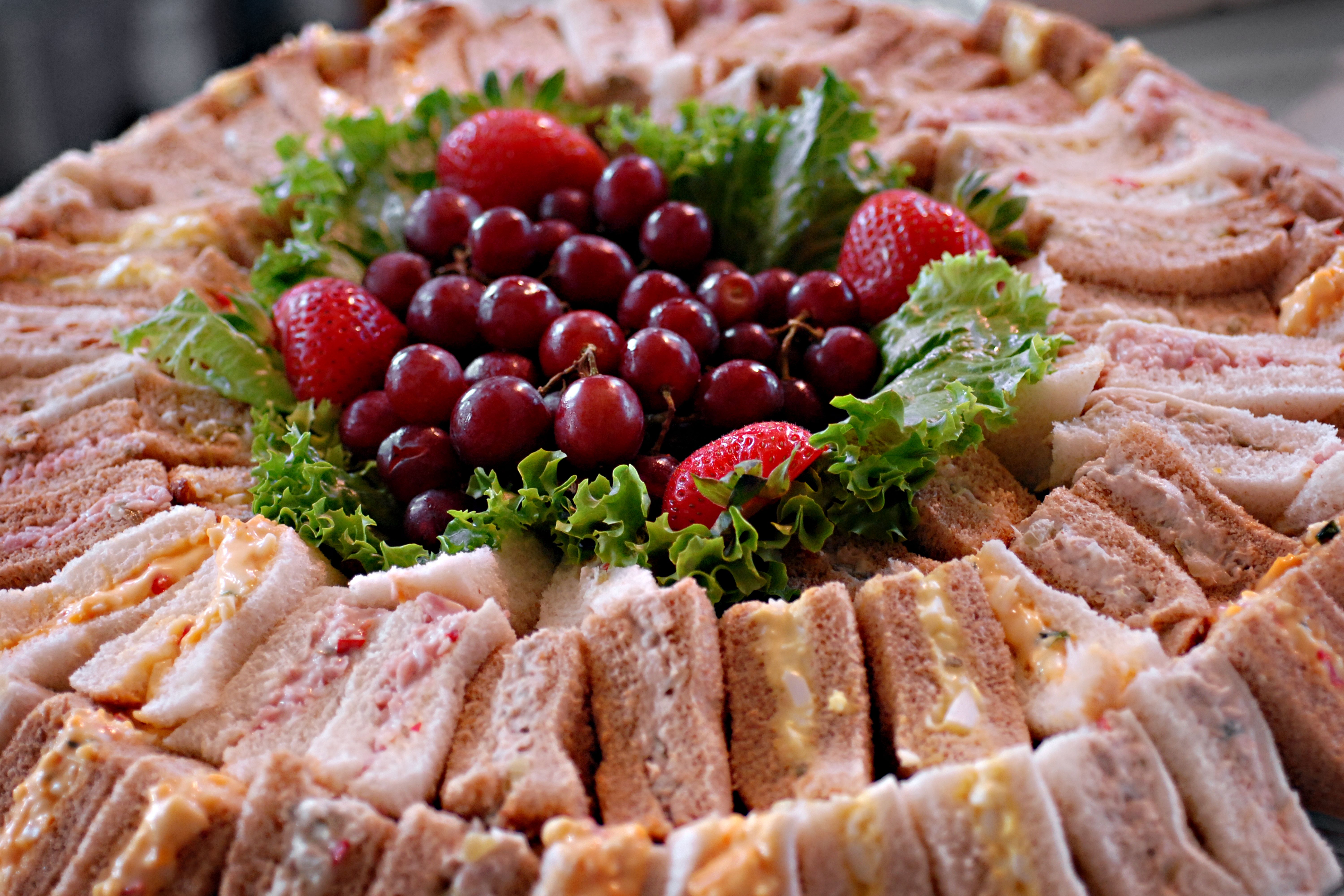Vibrant platter featuring assorted sandwiches, strawberries, and grapes with fresh lettuce garnish.