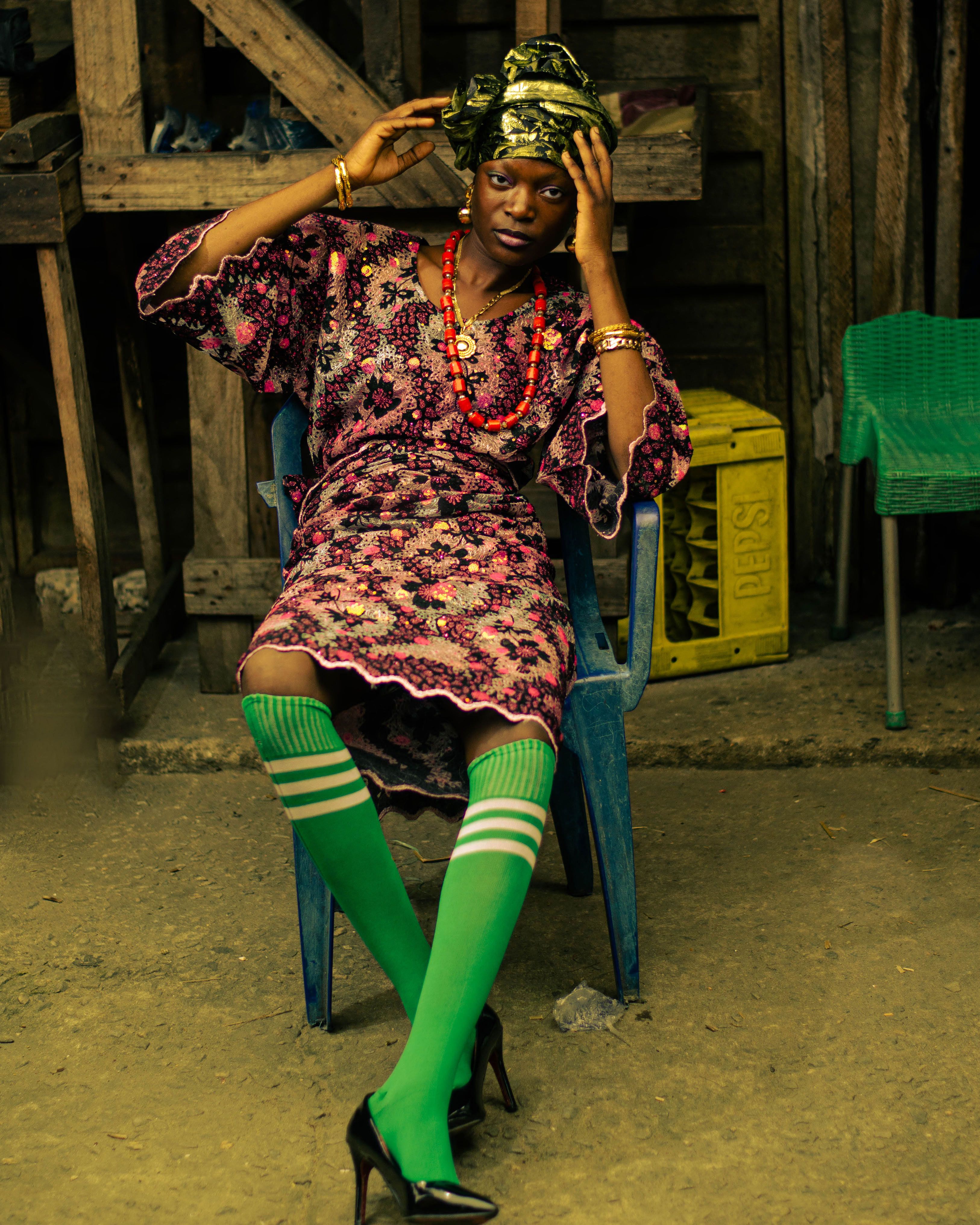 A stylish Nigerian woman in traditional dress sitting outdoors.