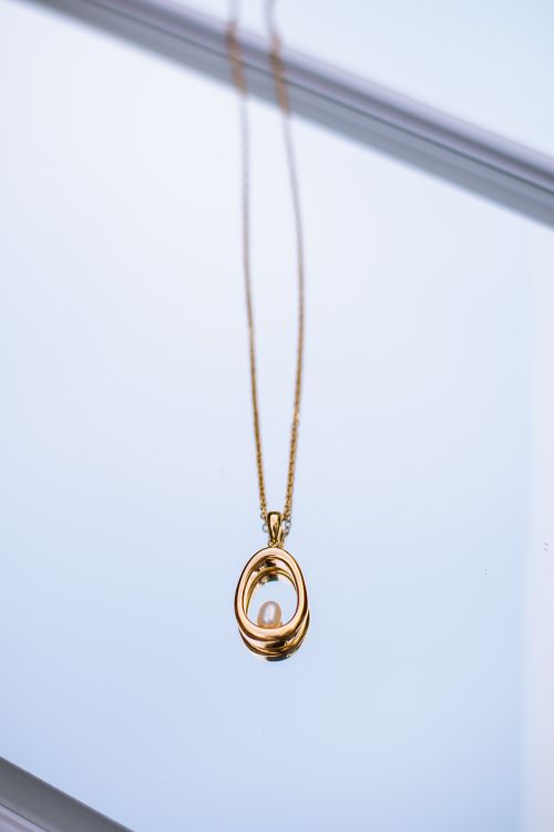 Free A minimalist gold necklace featuring an elegant pearl pendant, perfect for any occasion. Stock Photo
