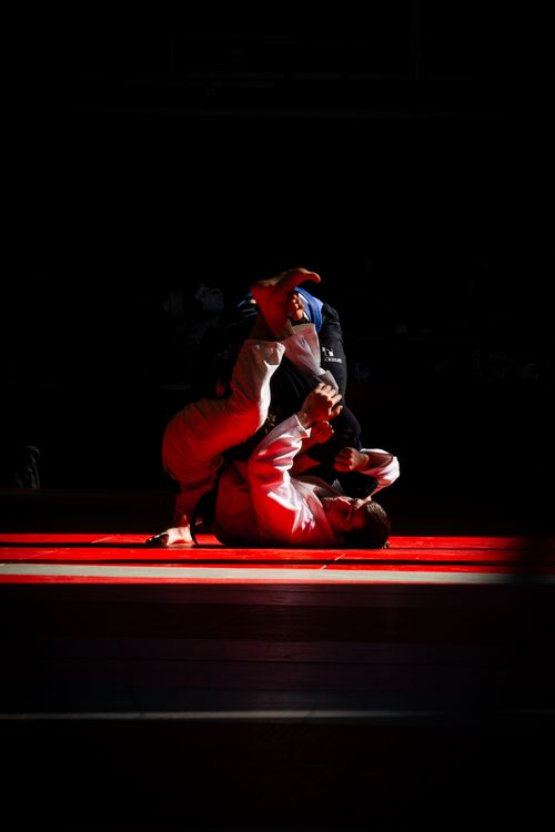 Free Intense Brazilian Jiu-Jitsu match showcasing skillful grappling on a mat. Stock Photo