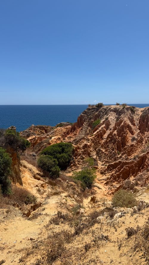 Free Stunning view of rugged cliffs and ocean under a clear blue sky in Algarve, Portugal. Stock Photo