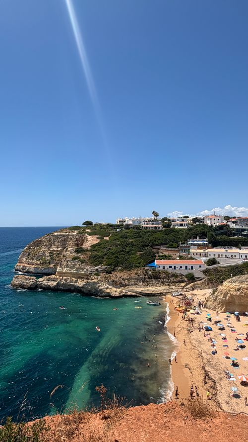Free Explore the scenic Algarve coastline with a stunning view of cliffs, azure waters, and a sunlit beach. Stock Photo