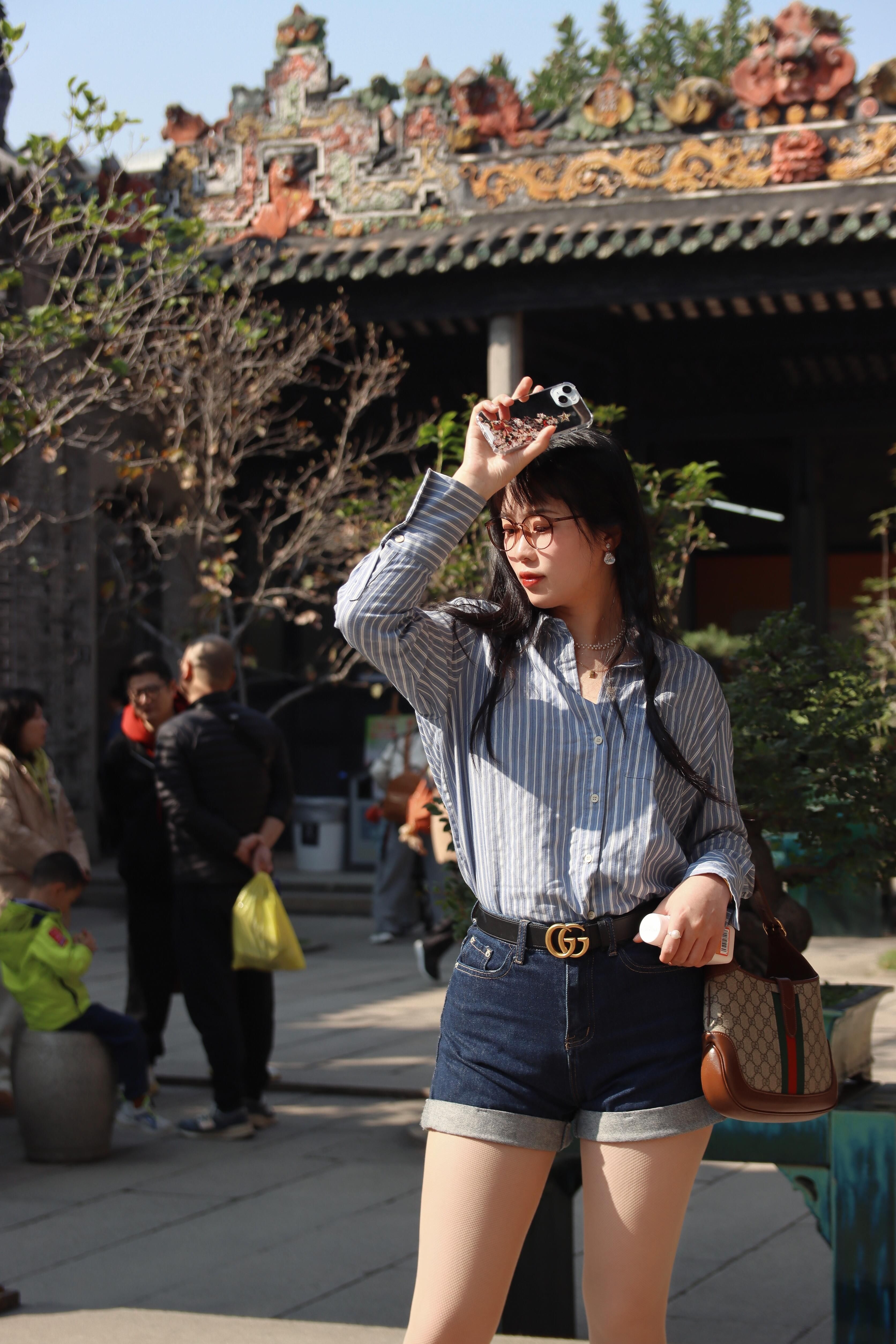 A fashionable young woman posing stylishly at a historical site in Nanjing, China, on a sunny day.
