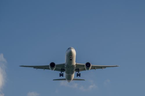 Free A commercial airplane flying overhead against a clear blue sky, capturing aviation in action. Stock Photo