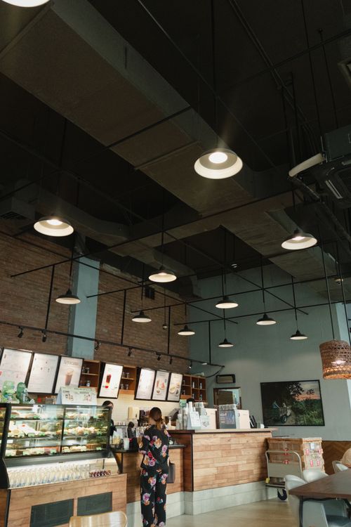 Free Cozy cafe interior featuring modern exposed ceiling lights and wooden decor for a relaxing ambiance. Stock Photo