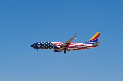 Free A Southwest Airlines plane with an American flag livery in flight against a clear blue sky. Stock Photo
