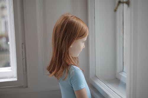 Girl in Blue T-shirt Looking Out the Window