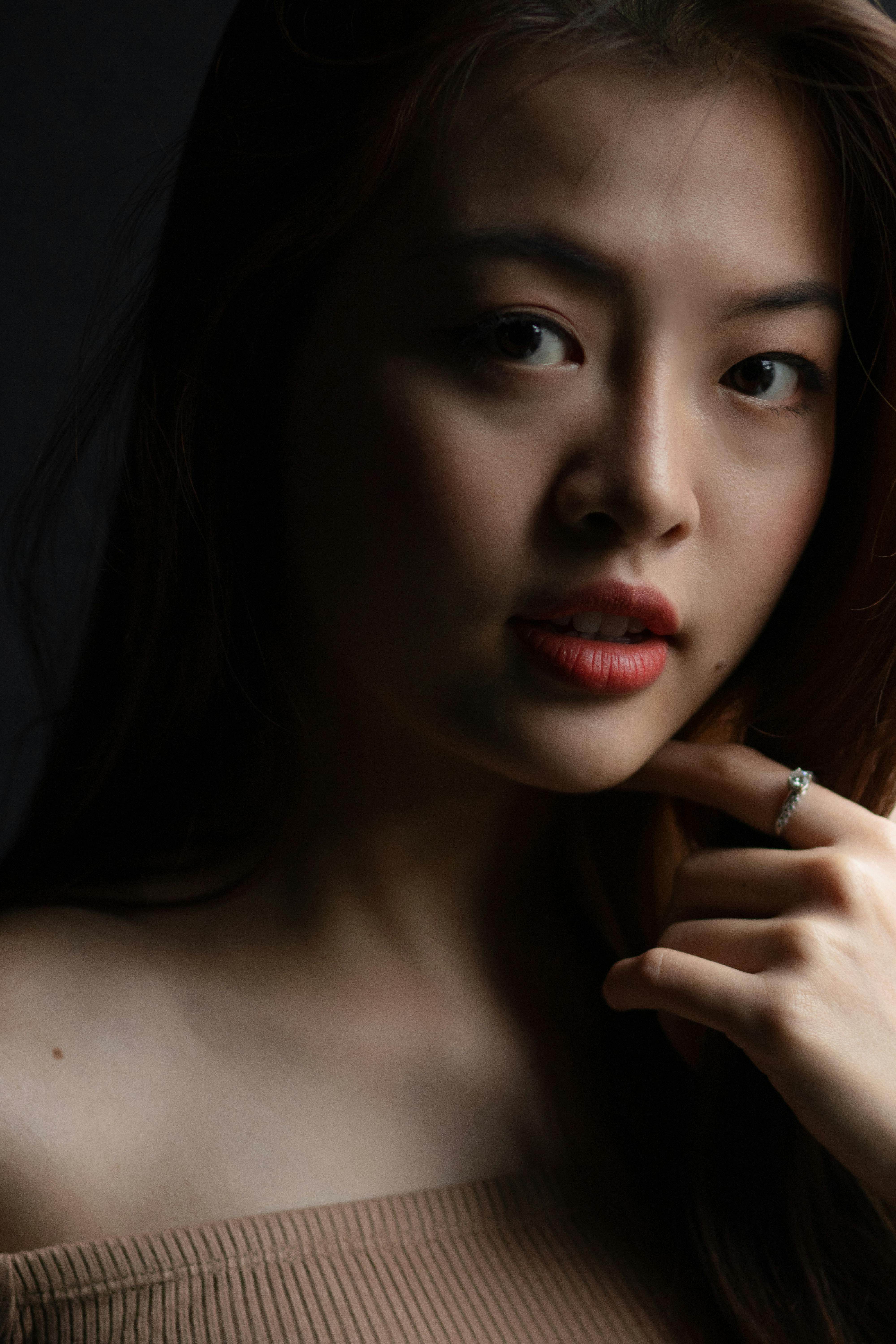 Striking portrait of a woman with red lipstick in soft lighting, exuding elegance.