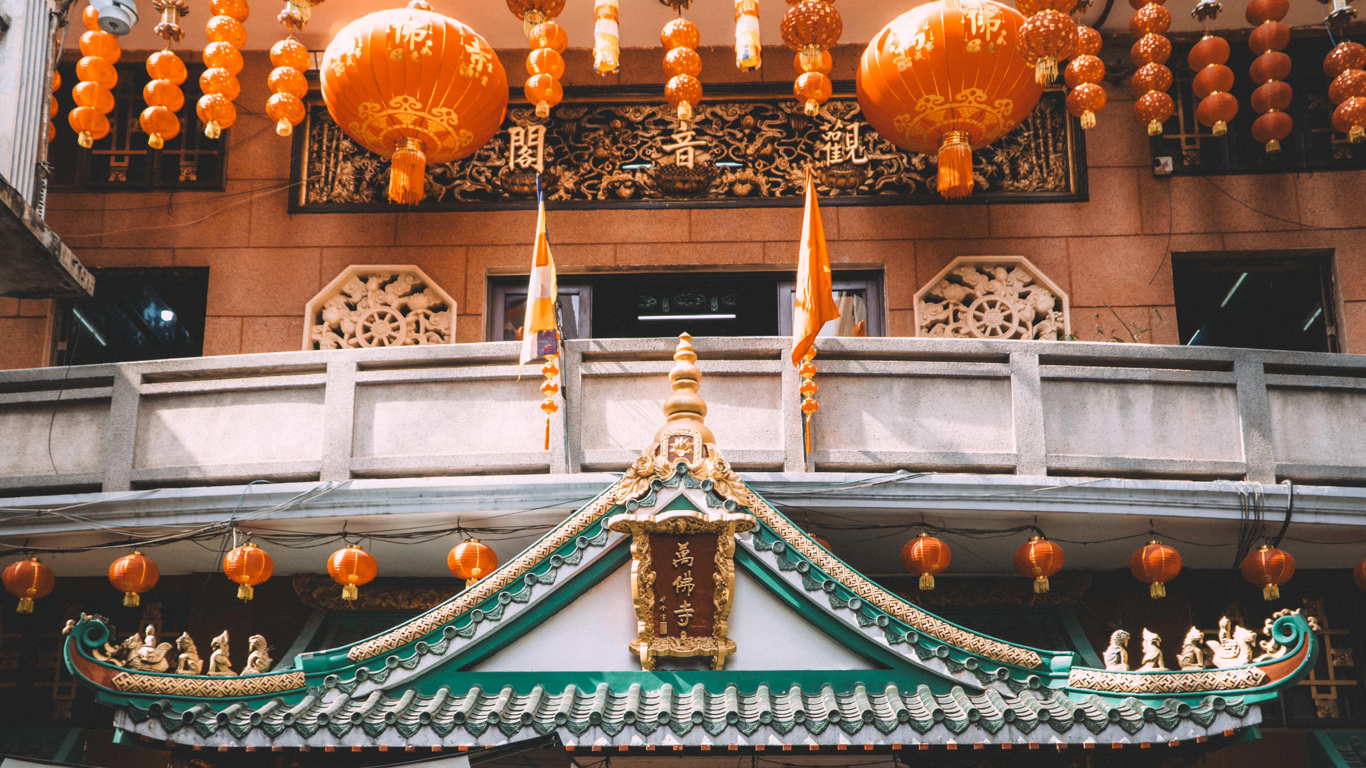 Decorative Chinese temple facade adorned with orange lanterns and intricate roof details.