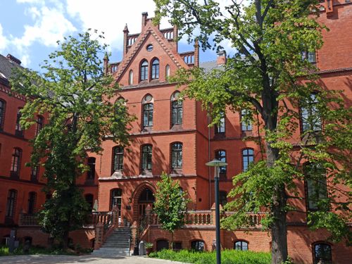 Free Charming Gothic Revival architecture in Wrocław, surrounded by lush greenery. Stock Photo