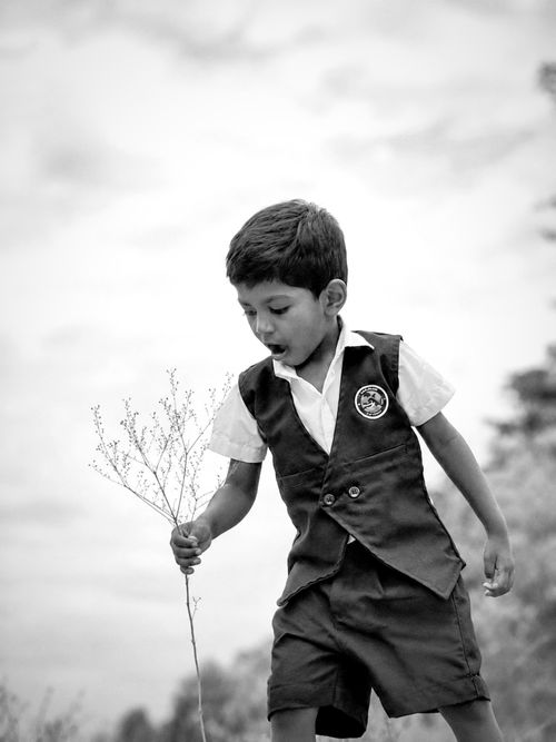 Free Monochrome photo of a young boy in a uniform holding a twig in Tiruppur, India. Stock Photo