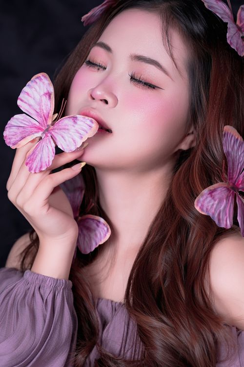 Free Beautiful portrait of a woman with pink butterflies embodying elegance and grace. Stock Photo