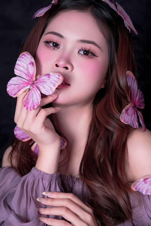Free Elegant portrait of a woman adorned with pink butterflies, blending beauty and nature. Stock Photo