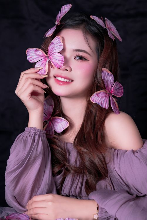 Free Close-up portrait of a smiling woman with purple butterflies in her hair. Stock Photo