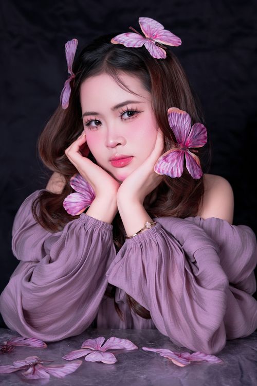 Free A stunning portrait of a young woman adorned with purple flowers in her hair and outfit. Stock Photo